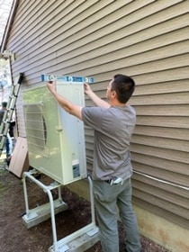A man installing a ductless split cooling system in a house in Lyme, CT.