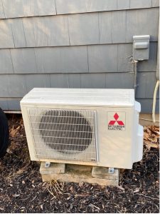 A Mitsubishi heat pump in front of a house.