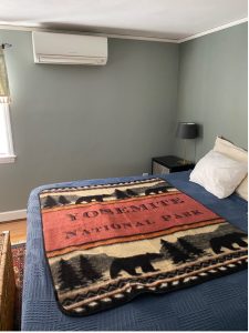 A bed with a blanket on it and an air conditioner, powered by the Mitsubishi Heat Pump.