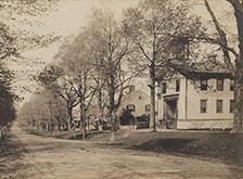 An old photo of a street with houses in Durham in the background.