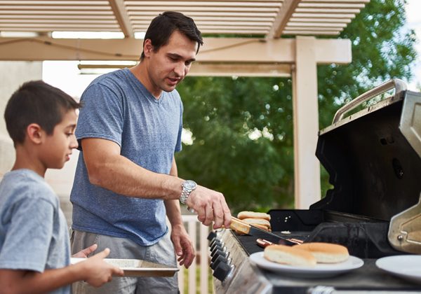 A man and a boy grilling food with propane.