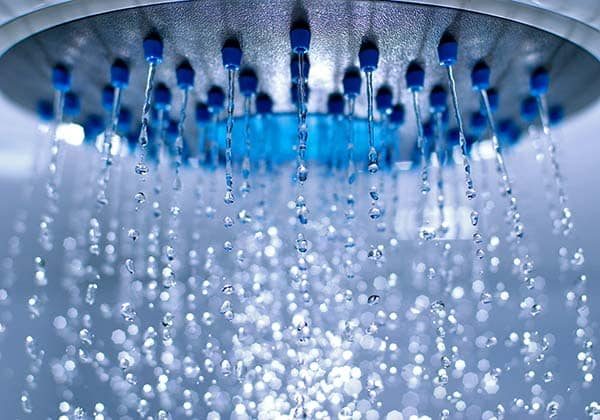 A close up of a shower head with blue water, powered by propane.